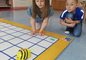 chłopiec z dziewczynką kodują pszczółkę BeeBot na macie do kodowania